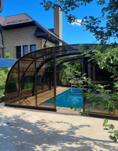 Композитный бассейн с раздвижным тёмно-коричневым павильоном и деревянным настилом на придомовой территории